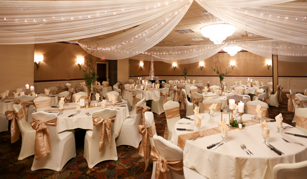 Wedding reception area with gold ribbons around white chairs