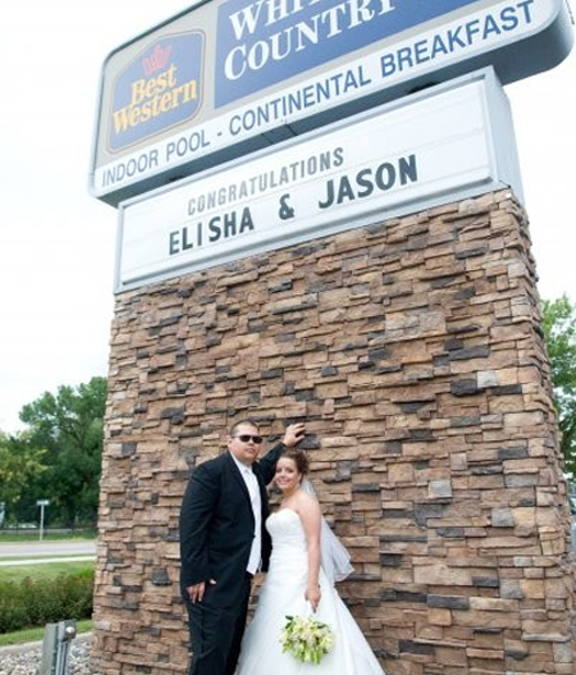 Bride and Groom standing by Best western sign